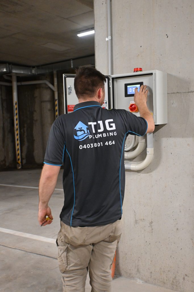 commercial maintenance plumber using switchboard in underground carpark