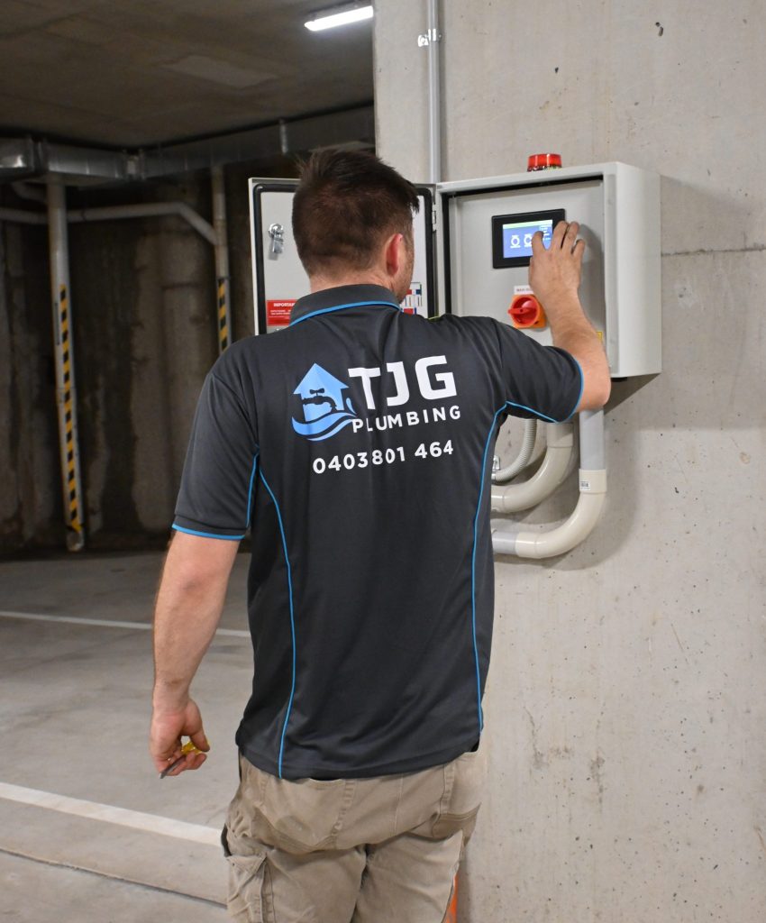commercial maintenance plumber using switchboard in underground carpark